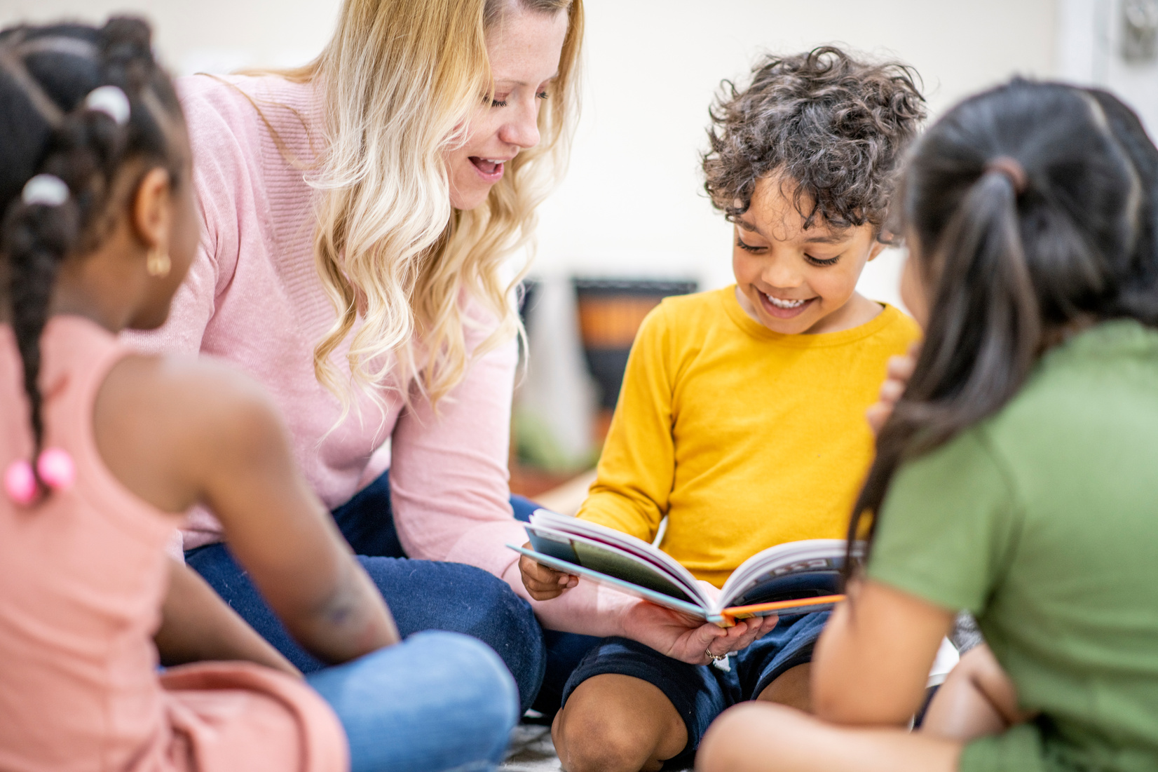 A teacher reading a picture book with a small group of young children