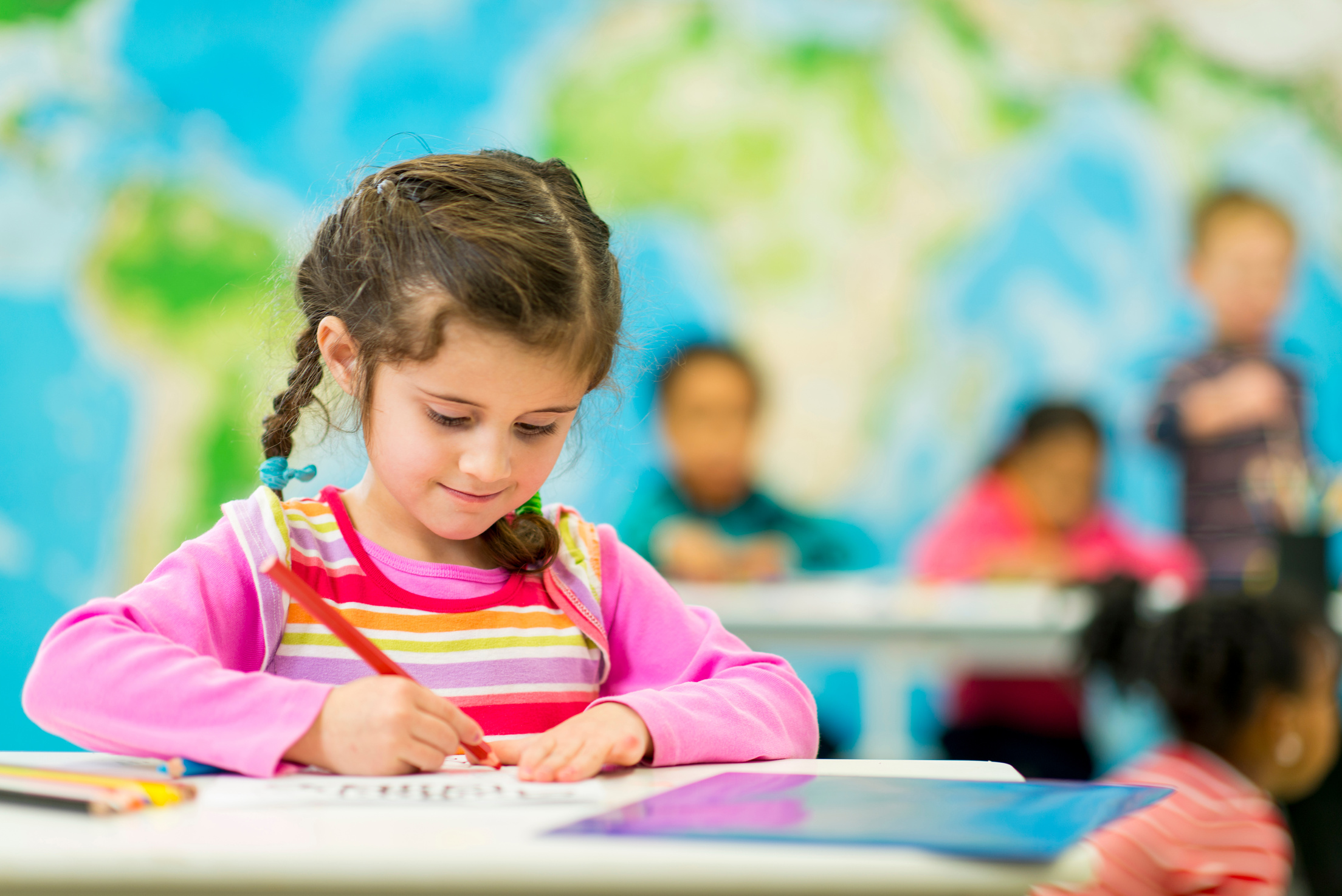 A child writing with a pencil on a worksheet at a desk